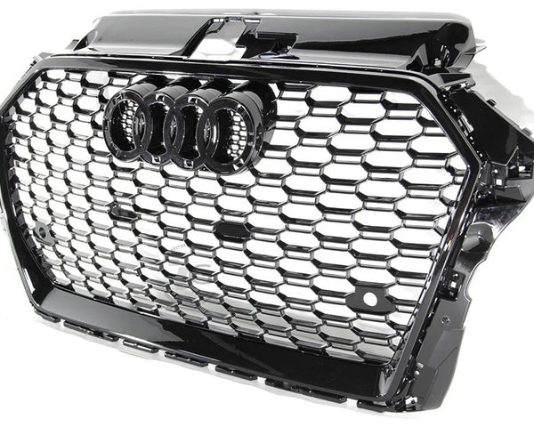 A black car grille showcases interlocking silver hexagonal patterns with a prominent set of four interlinked rings in the center, symbolizing a well-known automotive brand.