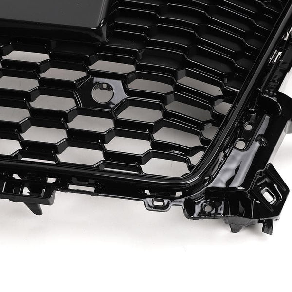 A black, honeycomb-patterned car grille with glossy finish, displayed at an angle on a plain white background.