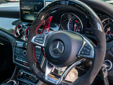 Steering wheel with multi-function controls sits inside a modern car interior, featuring a digital dashboard, infotainment screen, and climate controls. The Mercedes-AMG logo is visible on the steering wheel.