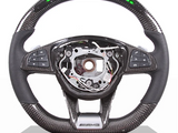 A carbon-fiber steering wheel features multifunction buttons on the sides and a digital display at the top. The center is missing, revealing internal mechanisms. Display text: 