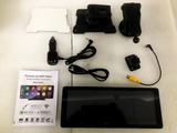 A collection of car accessories including a touchscreen, mounts, power adapter, and cables, arranged on a white foam surface. Includes manual: 