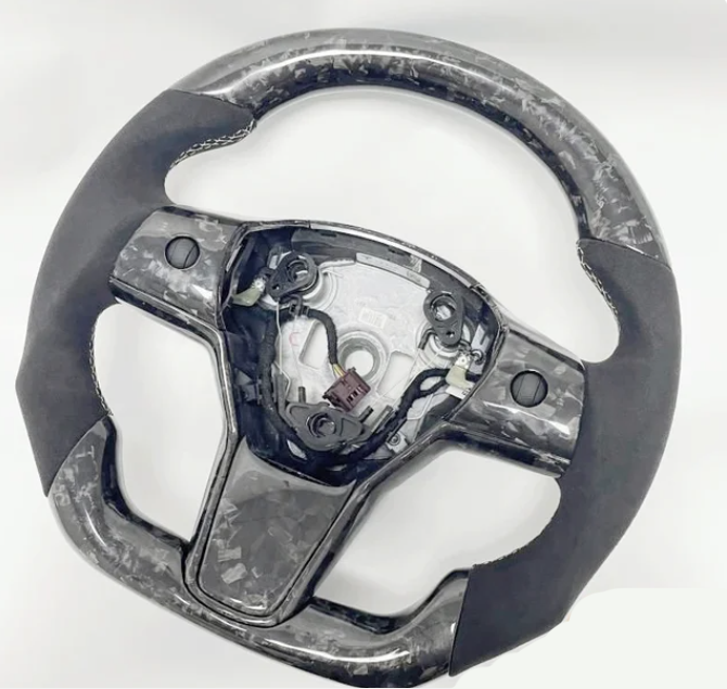 A steering wheel with a marbled pattern and missing central cover, exposing internal wiring and mechanisms, set against a plain white background.
