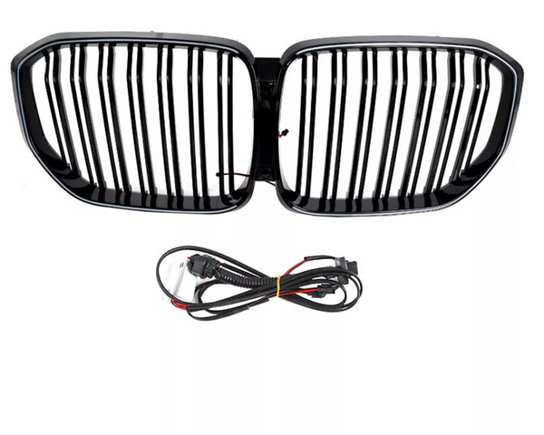 A black car grille with vertical slats is positioned above a coiled set of black electrical cables, both set against a plain white background.