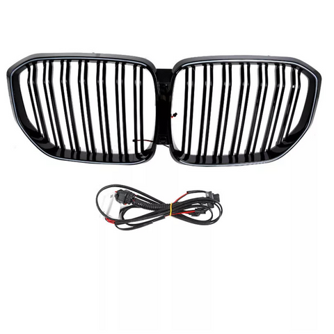 A black car grille with vertical slats is positioned above a coiled set of black electrical cables, both set against a plain white background.