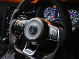 Steering wheel with Volkswagen emblem, equipped with control buttons, is positioned in front of illuminated car dashboard displaying speedometers and digital gauges in a dimly lit vehicle interior.