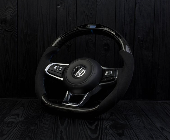 A Volkswagen steering wheel, featuring buttons and a sleek design, rests against a dark, textured wooden backdrop.