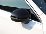 A black side mirror is attached to a white car, reflecting light in a sunny outdoor setting. The vehicle's window and frame are partially visible.