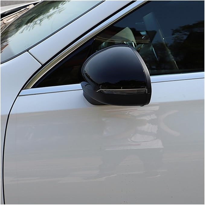 A black side mirror is attached to the passenger side of a white car, reflecting nearby trees and sky in a parking lot setting.