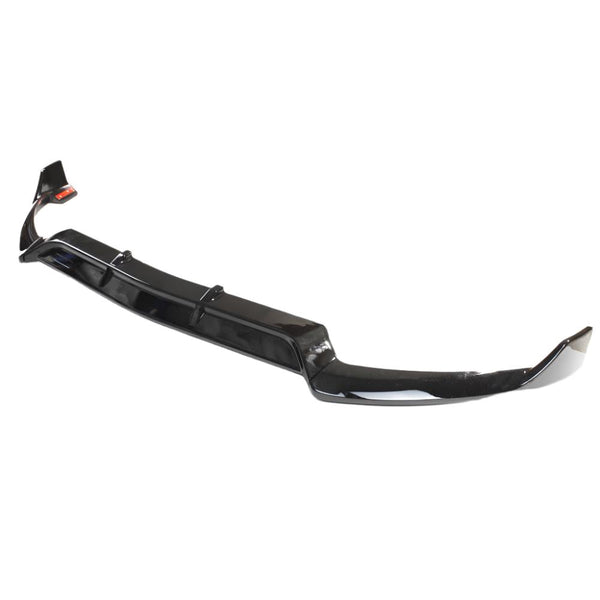 A glossy black car front lip splitter lies on a plain white background, showcasing its curved aerodynamic design and streamlined edges.
