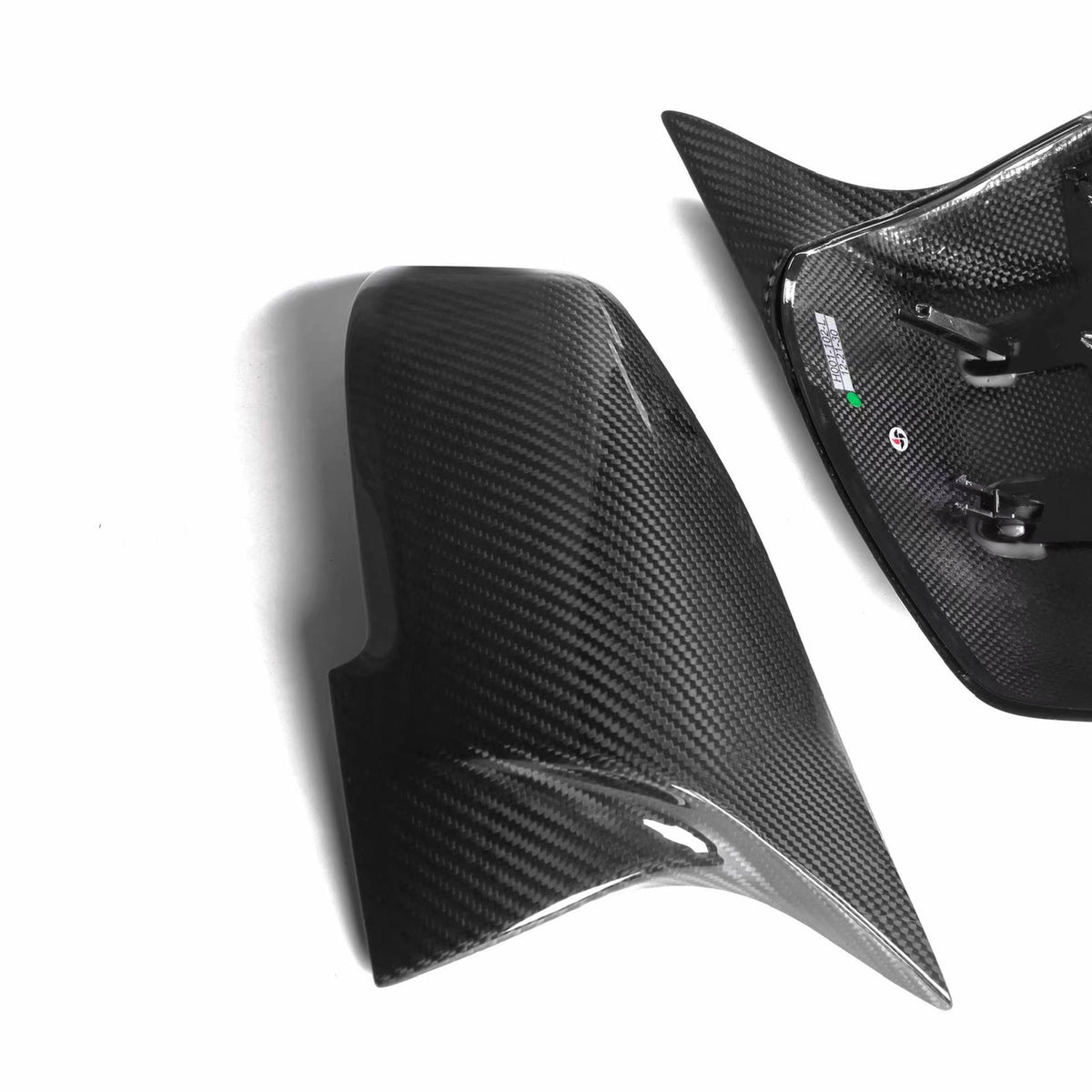 Carbon fiber car side mirror covers, one showing the glossy exterior and the other showcasing the interior attachment points, placed against a plain white background.