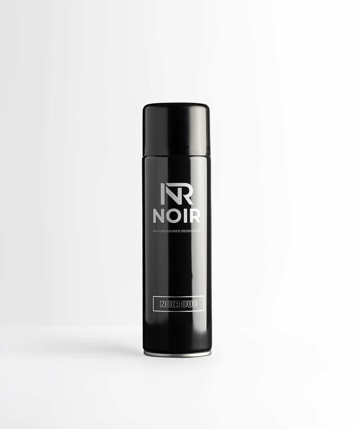 A black cylindrical deodorant can stands on a white surface. Text reads: "NR NOIR HIGH PRESSURED DEODORISER NOIR OUD." The background is a plain white wall.
