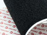 A roll of black Velcro material lies on paper printed with 