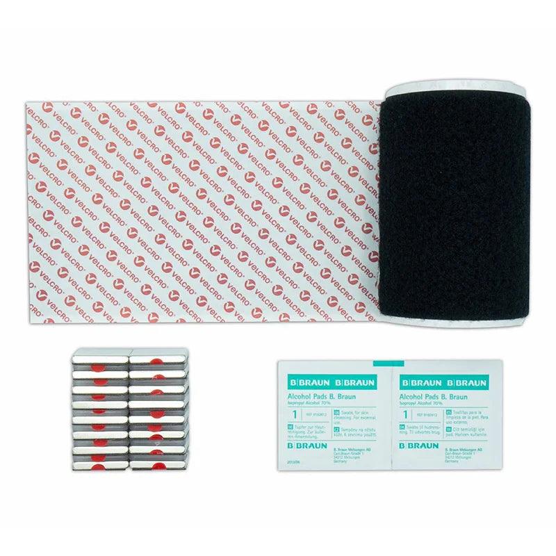 A collection of medical supplies including a black Velcro band, adhesive strips labeled "VELCRO," stacked gray cylinders with red markings, and two alcohol pads labeled "B BRAUN Alcohol Pads B. Braun."