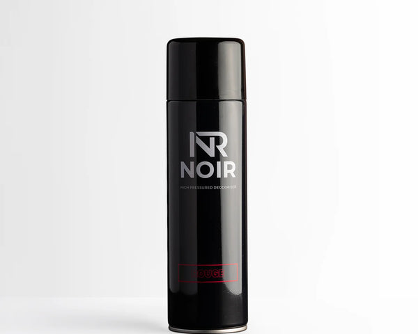 A black aerosol can labeled “NR NOIR” and “HIGH PRESSURED DEODORISER” stands upright on a plain white surface. The word “ROUGE” is in red near the base.