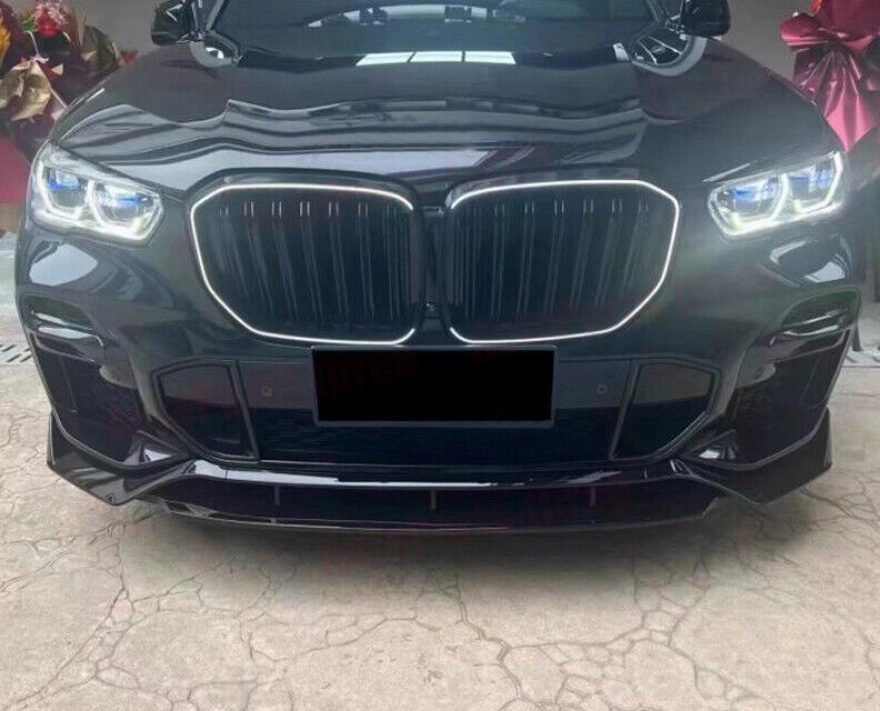 A black car's front view shows a large grille and illuminated headlights, parked on a concrete surface. Red ribbons in the background suggest a celebratory or gifting context.