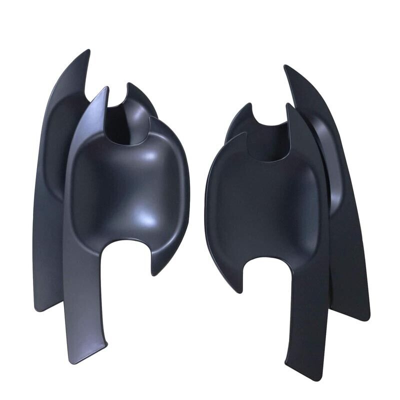 Two black, abstract chair-like objects with curved and pointed features stand upright against a plain white background, resembling stylized sculpture or modern art pieces.