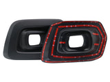 Two black, rectangular plastic components with hollow centers are shown. One is plain, while the other is bordered by red strips of adhesive tape, placed on a white background.