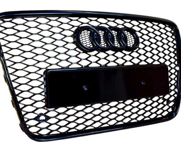 A black, honeycomb-patterned car grille featuring four linked rings at the top, with a rectangular placeholder for a license plate, set against a white background.