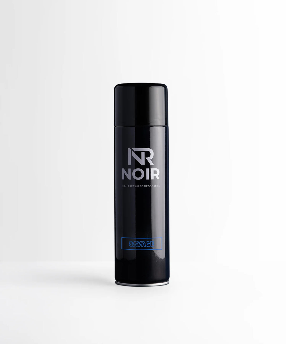 A black cylindrical deodorant can stands upright on a white surface. Text on the can reads "NR NOIR HIGH PRESSURED DEODORISER SAVAGE," set in a minimalistic and bright environment.