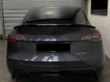 A black Tesla car is parked inside a garage. The back features 