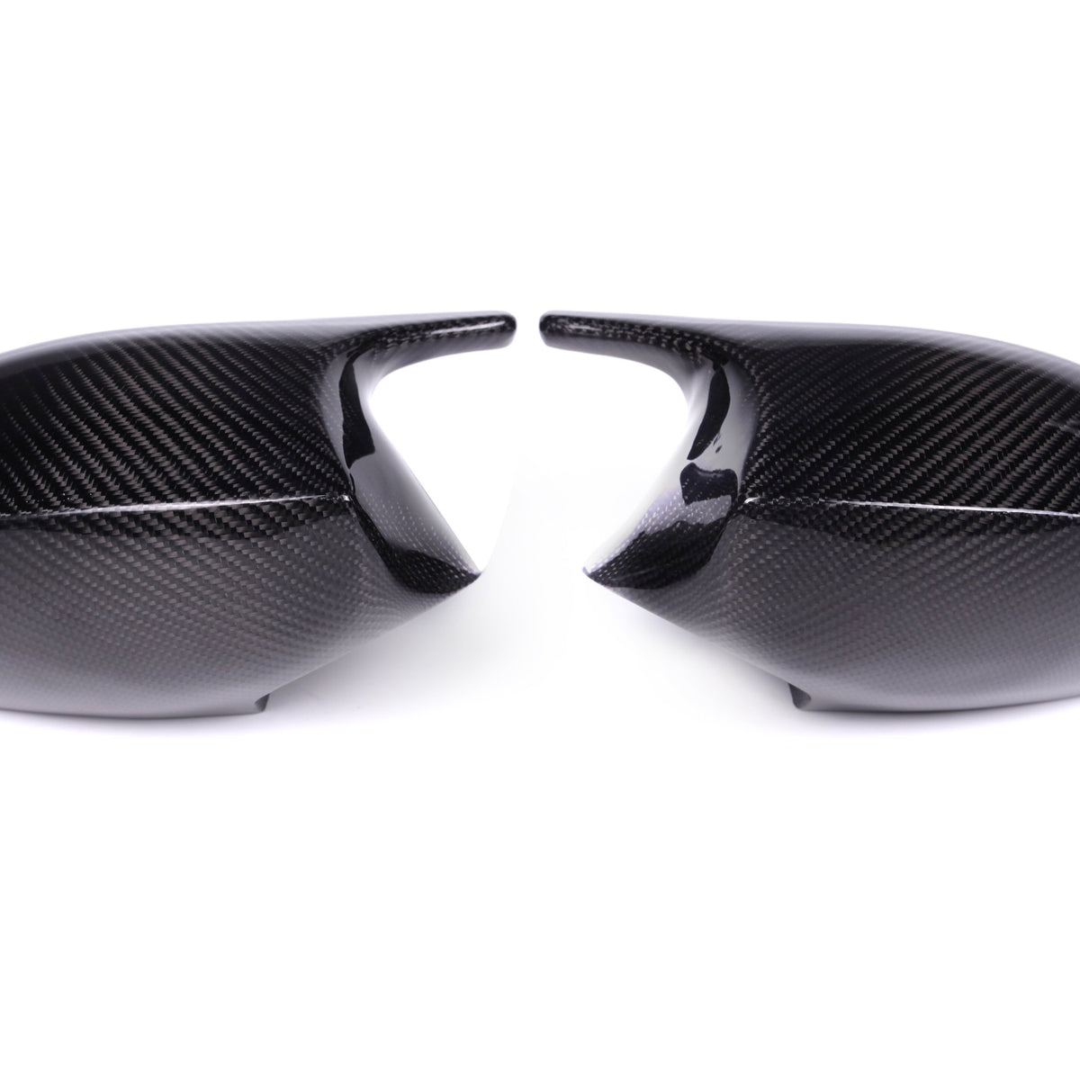 Two carbon fiber car mirror covers face each other against a plain white background, displaying a sleek, glossy surface with a distinct woven pattern.