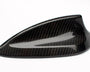A carbon fiber car antenna cover with a sleek, aerodynamic design rests on a plain, white background.