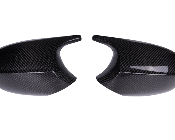 Two black carbon fiber car mirror covers are placed side by side on a plain white background, showcasing a glossy finish and a textured pattern.