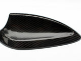 A carbon fiber car antenna cover rests on a white background, showcasing its glossy, textured surface with a sleek, aerodynamic design.