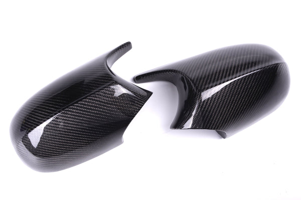 Two glossy carbon fiber mirror covers, resting on a white background, feature a distinctive woven texture and sleek contours.