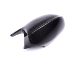 A sleek, black carbon fiber side mirror cover sits on a white background, displaying its glossy finish and textured pattern, suggesting automotive use.