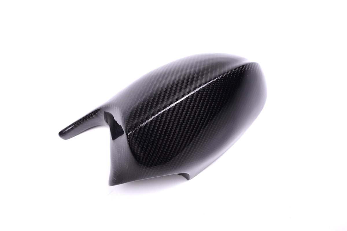 A sleek, black carbon fiber side mirror cover sits on a white background, displaying its glossy finish and textured pattern, suggesting automotive use.