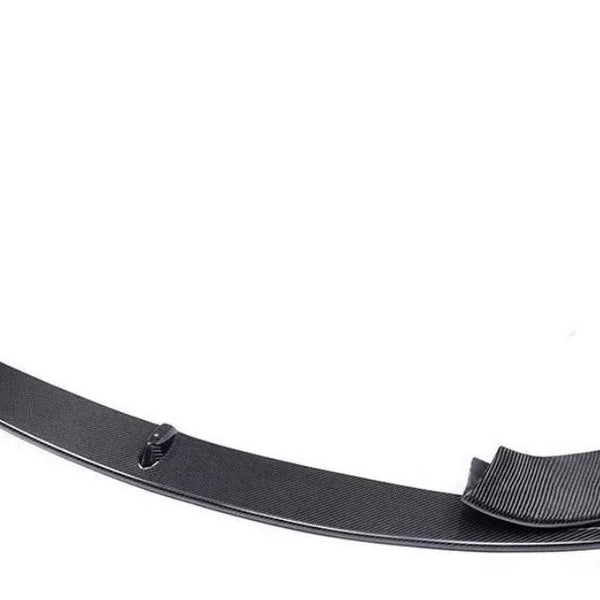 Carbon fiber car bumper lip sits on a plain white surface, showcasing its curved design and textured finish, with raised ends for aerodynamic improvement.