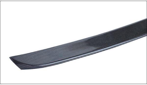 A carbon fiber ski tip, curved slightly upward, features a textured pattern. It is set against a plain white background, emphasizing the sleek design and material.