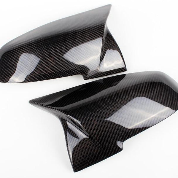 Two glossy carbon fiber car mirror covers are displayed on a white background, showcasing their sleek, aerodynamic design and checkered pattern.
