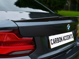 A car's rear shows a sleek spoiler and a visible logo, with text reading 