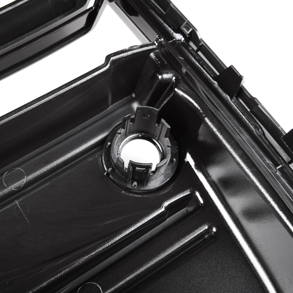 A glossy black plastic automotive part with a circular mount and ridges is shown in close-up, likely part of a larger engine or mechanical assembly.