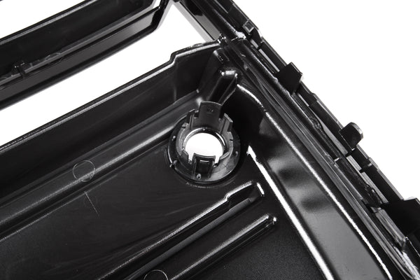 A glossy black plastic automotive part with a circular mount and ridges is shown in close-up, likely part of a larger engine or mechanical assembly.