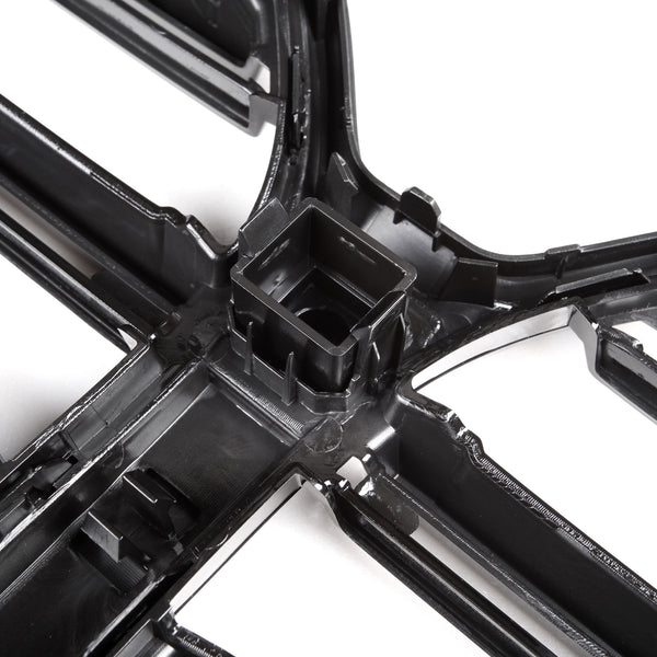 A black plastic grid structure sits on a white background, featuring intersecting lines with a central square cavity, likely part of an automotive or industrial component.
