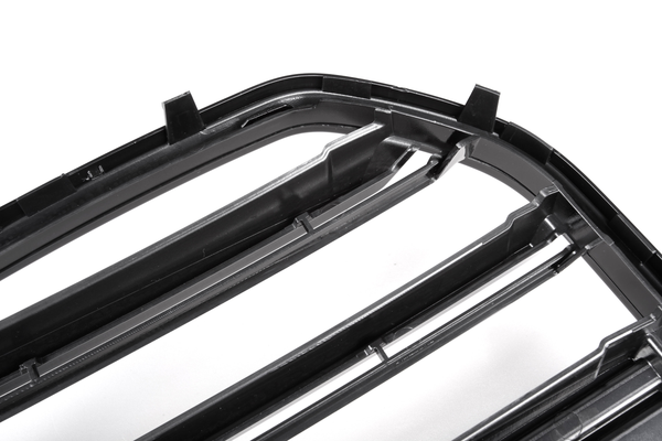 A black plastic car grille with horizontal slats, positioned diagonally, on a plain white background, highlighting the structure and texture of the material.