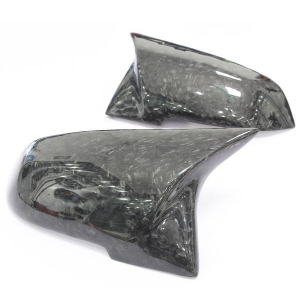 Two carbon fiber side mirror covers rest on a white background, showcasing a sleek, glossy finish with a textured pattern.