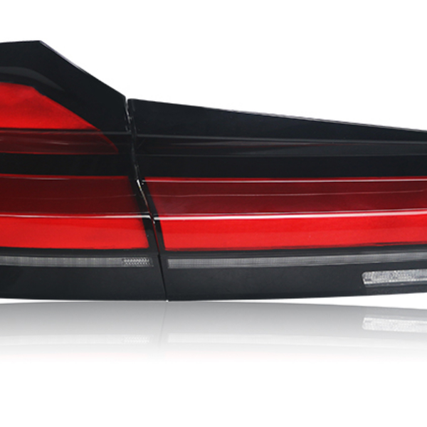 A sleek, red and black car taillight is shown reflecting light on a white surface, implying a modern automotive design.