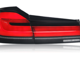 A red and black car taillight is positioned against a white background, highlighting its sleek, angular design with multiple segments and reflective surfaces.