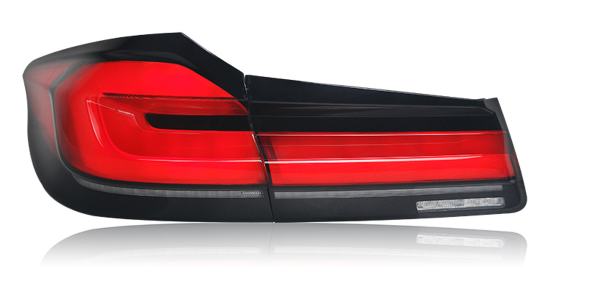 A red and black car taillight is positioned against a white background, highlighting its sleek, angular design with multiple segments and reflective surfaces.
