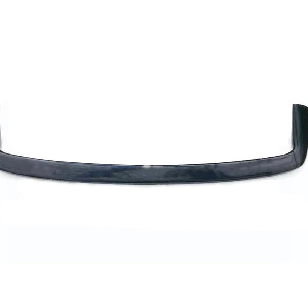 A sleek, black car spoiler with an upward curve lies on a white background, highlighting its aerodynamic design features.