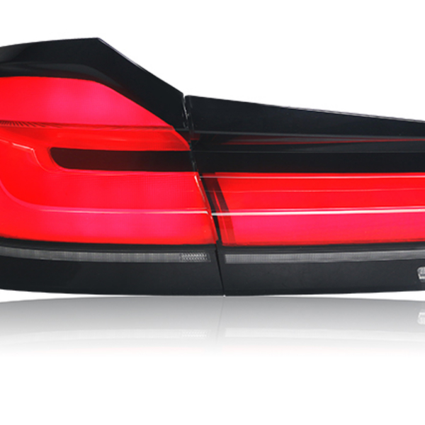 A red car taillight is illuminated, displaying sleek horizontal lines. It is isolated against a white background, highlighting the light's modern design and glossy finish.