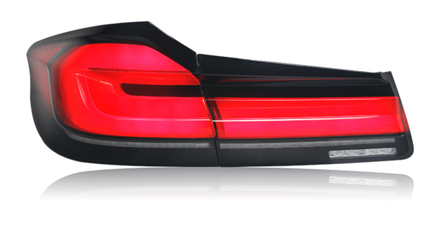 A red car taillight is illuminated, displaying sleek horizontal lines. It is isolated against a white background, highlighting the light's modern design and glossy finish.