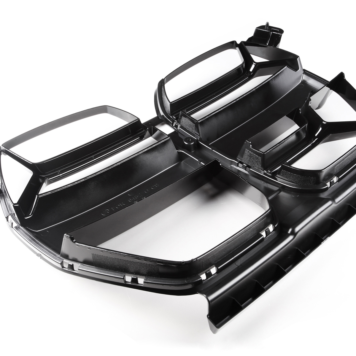 Black plastic automotive grille on a white background, featuring multiple rectangular openings and angular design elements, resting flat with a reflective sheen highlighting its contours.