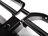 Black, glossy plastic car grille features multiple intersecting bars and rectangular openings, angled diagonally. Set against a white background, evoking a sleek, modern automotive part.