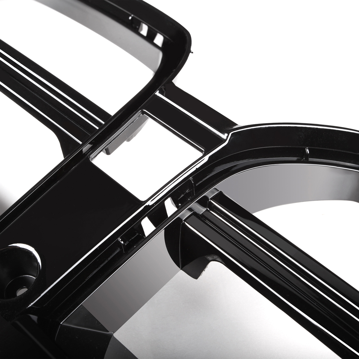 Black, glossy plastic car grille features multiple intersecting bars and rectangular openings, angled diagonally. Set against a white background, evoking a sleek, modern automotive part.