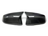 Two carbon fiber car wing mirror covers lie side by side, angled outward on a white background, showcasing a sleek, reflective design with a textured pattern.
